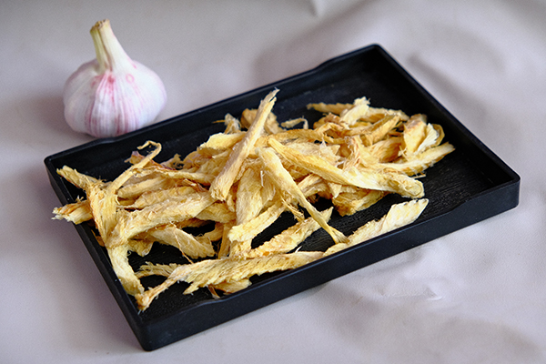 Strands of yellow sun-dried pollock slices for snacks